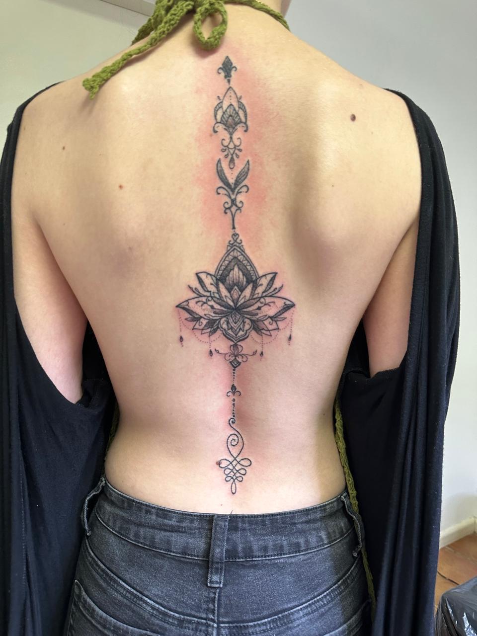 Ornamental lotus spine tattoo — healed result